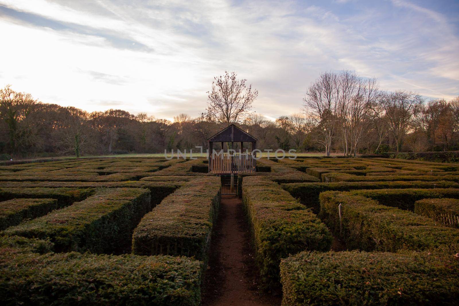 A wood cabin inside a maze in a park at sunset