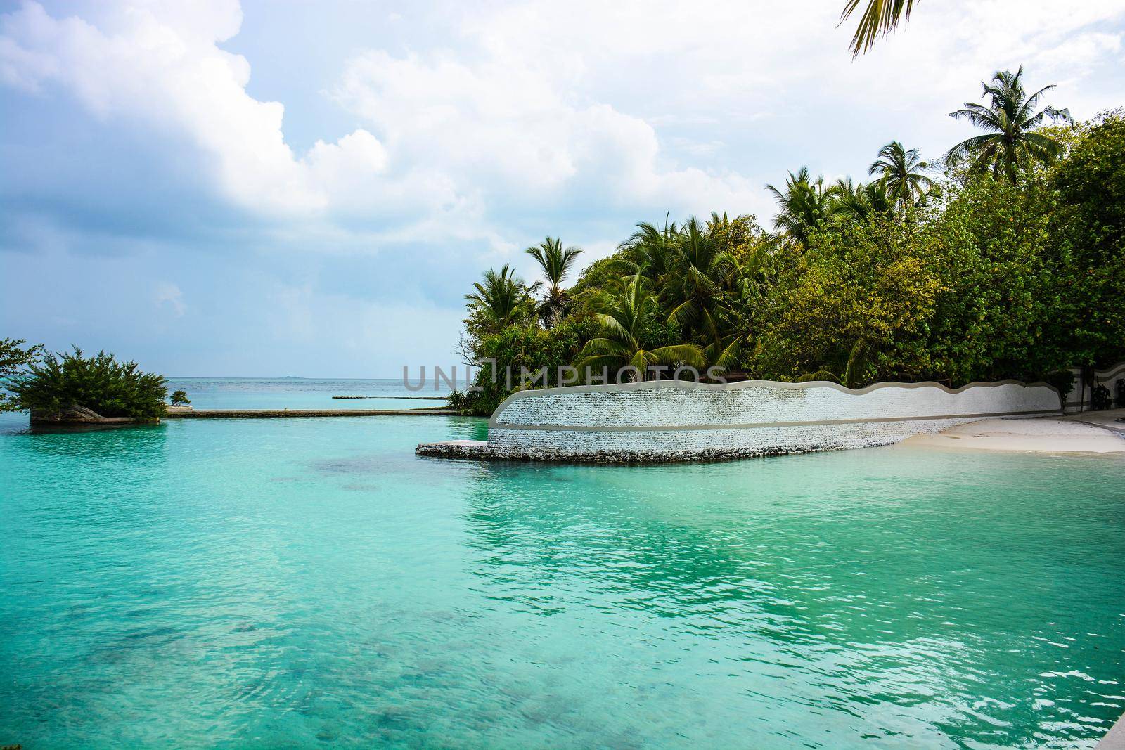 atoll of the tropics and maldives that are reflected in a sea of emerald with a cobalt blue sky