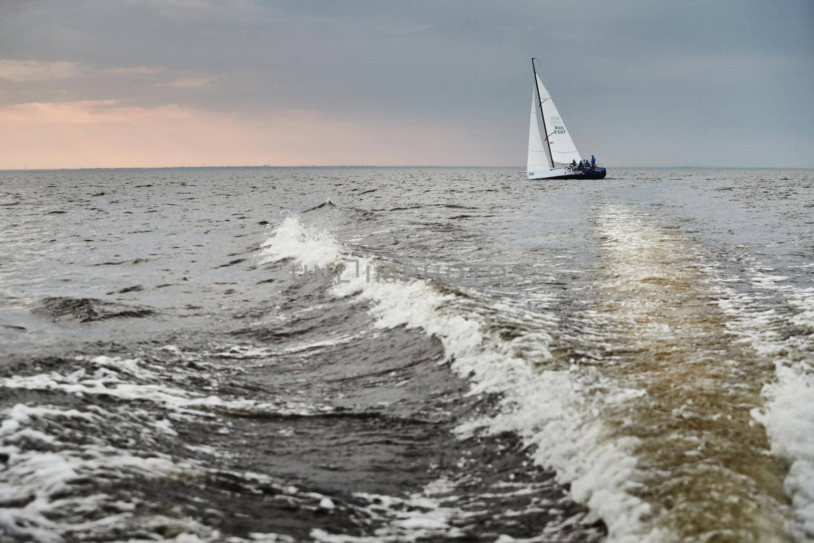 Russia, St.Petersburg, 05 September 2020: The lonely sailboat in a list goes by sea, the sky of pink color, the storm sky. High quality photo