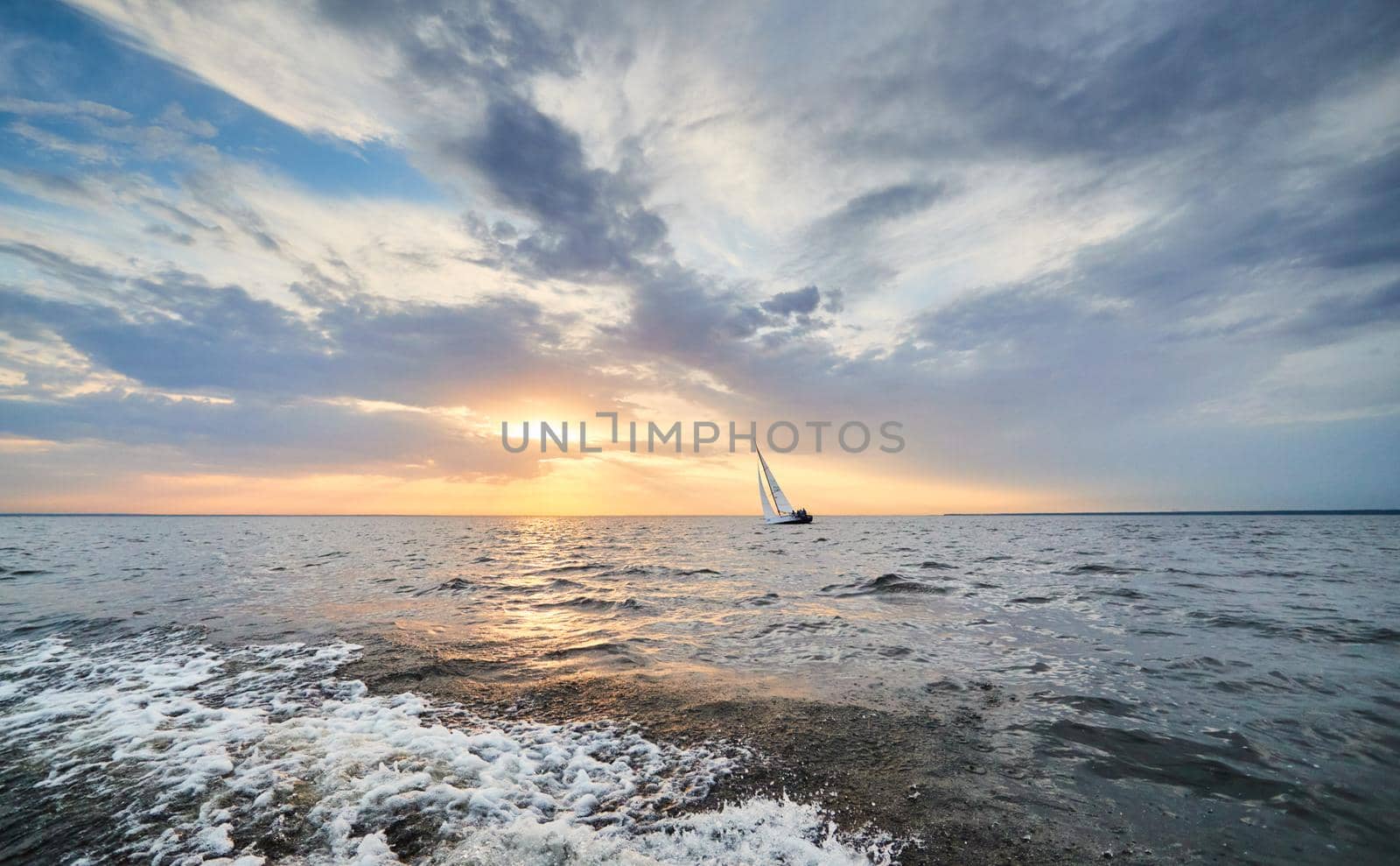Russia, St.Petersburg, 05 September 2020: The lonely sailboat in a list goes by sea, the sky of pink color, the storm sky. High quality photo