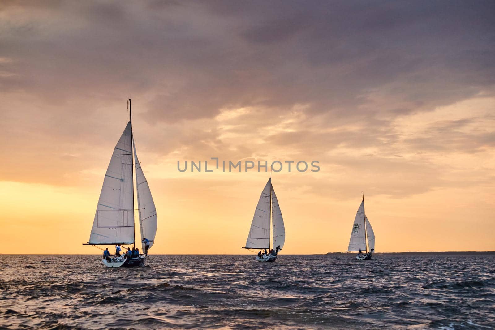 Russia, St.Petersburg, 05 September 2020: Some sailboats in a list goes by sea, the sky of pink color, the storm sky, regatta. High quality photo
