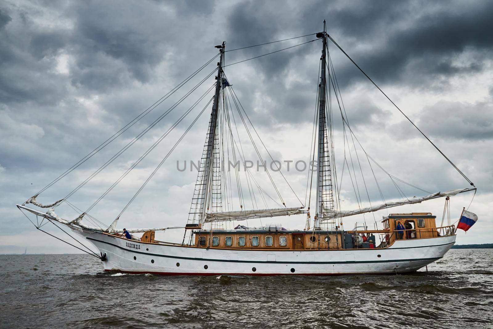 Russia, St.Petersburg, 31 August 2020: Antique sailing frigate of white color to the sea, the lowering storm sky, sails are lowered, masts and ropes by vladimirdrozdin