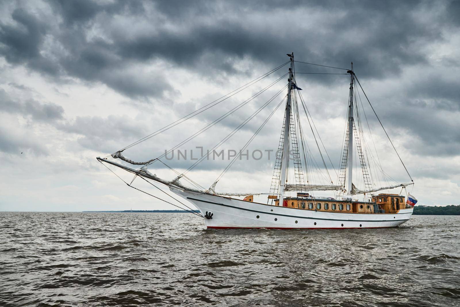 Antique sailing frigate of white color to the sea, the lowering storm sky, sails are lowered, masts and ropes. High quality photo