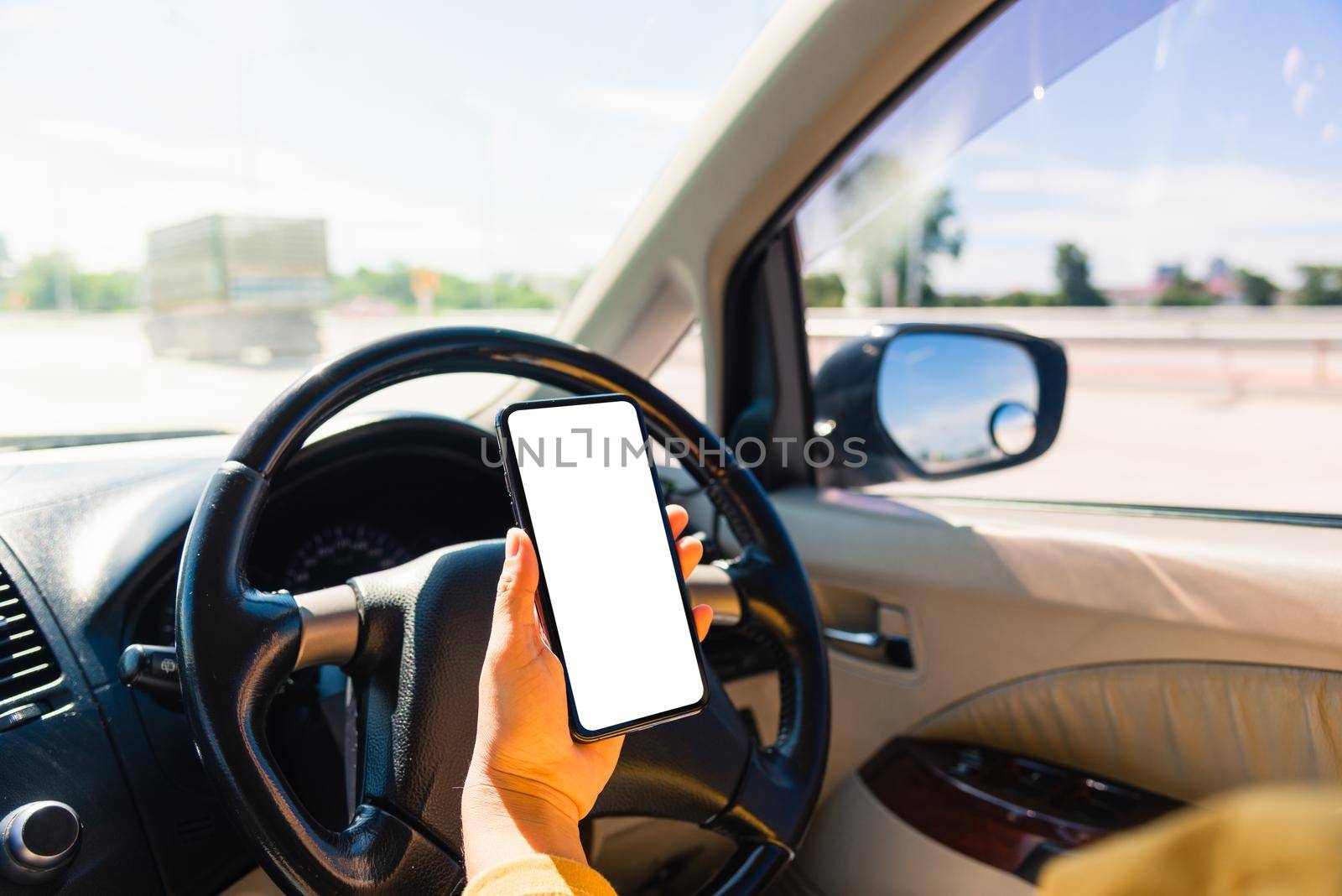woman inside a car and using a hand holding mobile smartphone blank screen while driving the car by Sorapop