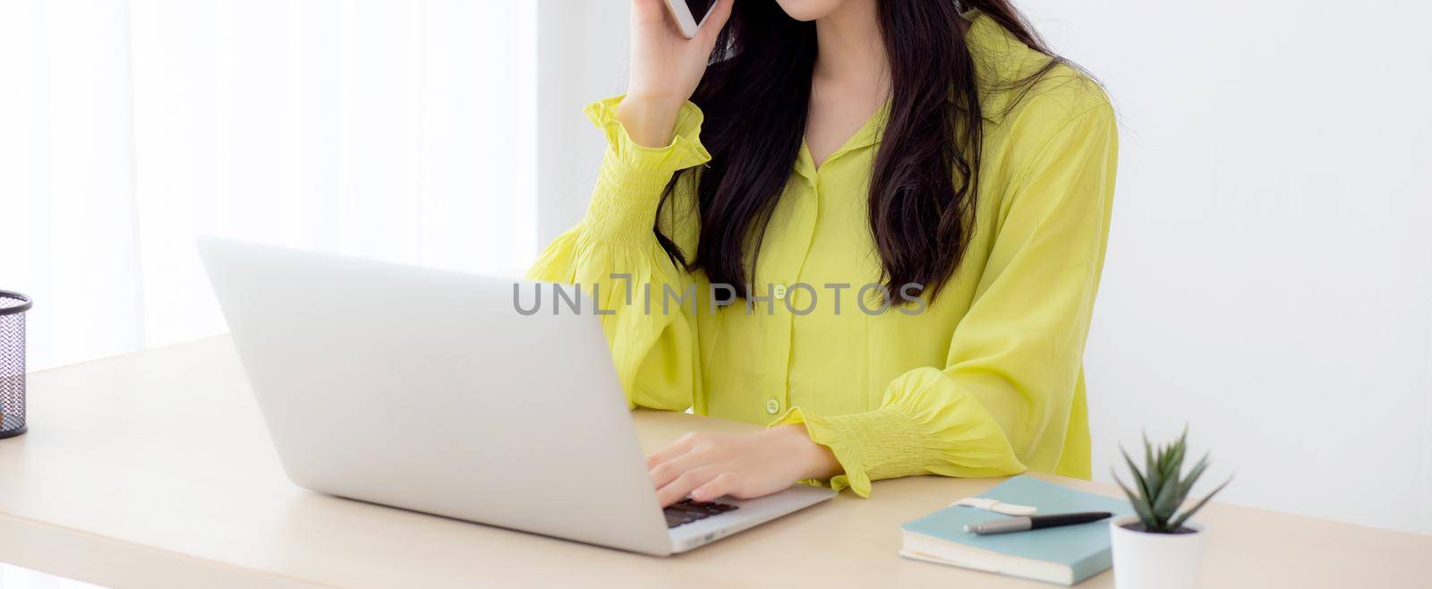 Young asian business woman working form home office and call phone for success at home, businesswoman using laptop computer on desk, female talking smartphone at workplace, communication concept. by nnudoo