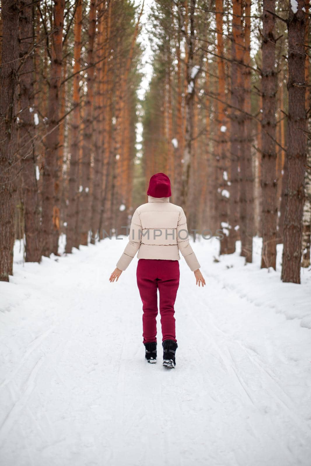 Winter walk in a snow-covered forest, A girl with a red jumpsuit  by AnatoliiFoto