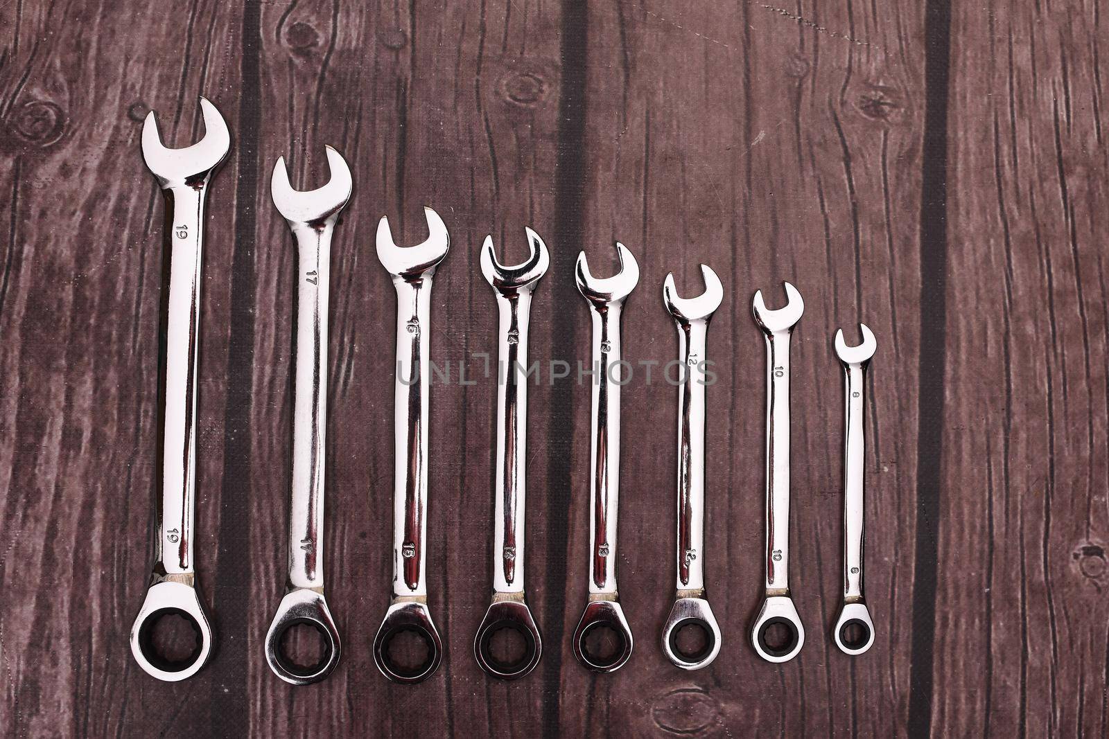 a set of spanners on a wooden background. a tool of chrome-plated shiny ratchet keys.