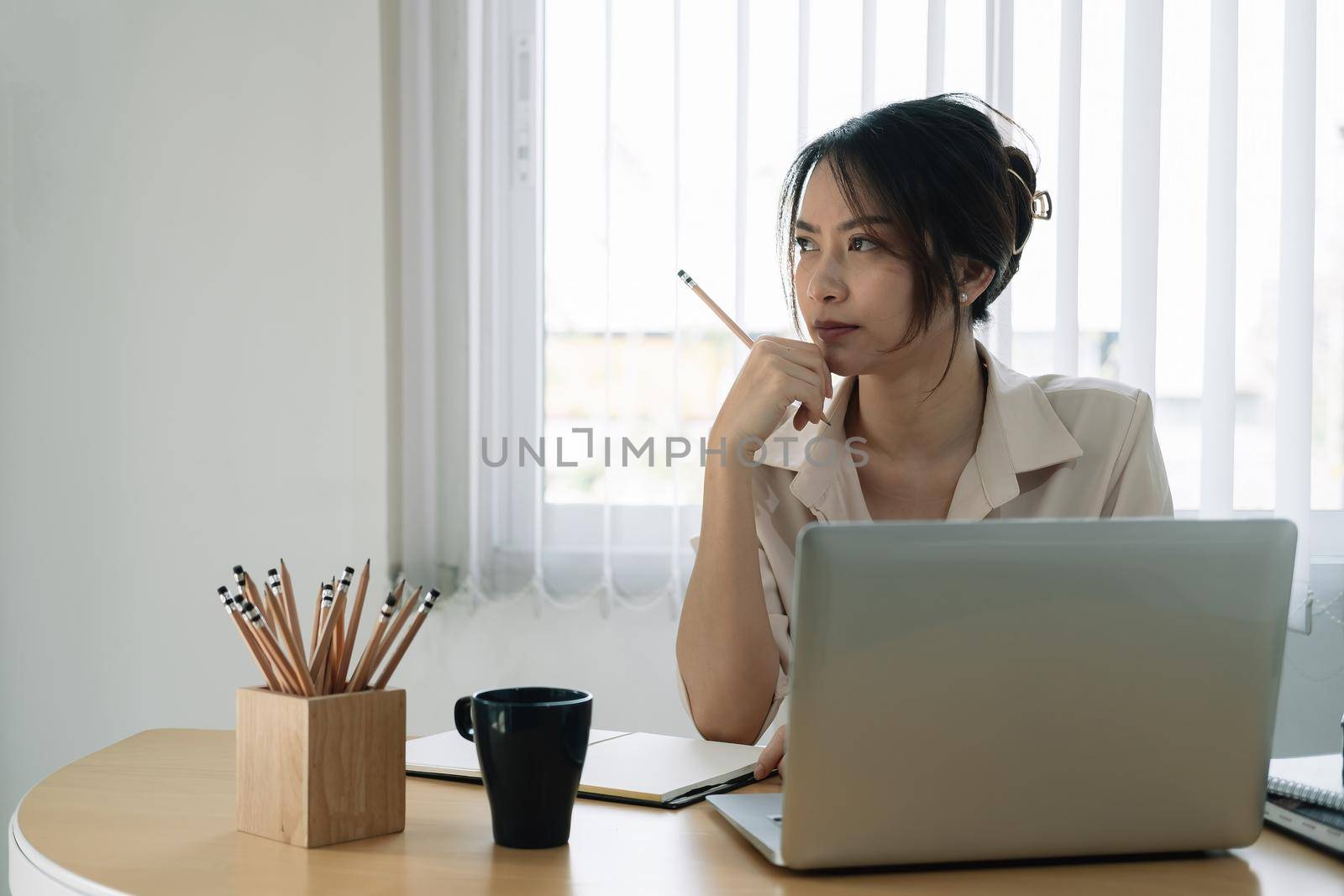Portrait of business asian woman thinking and working with laptop computer in office by nateemee