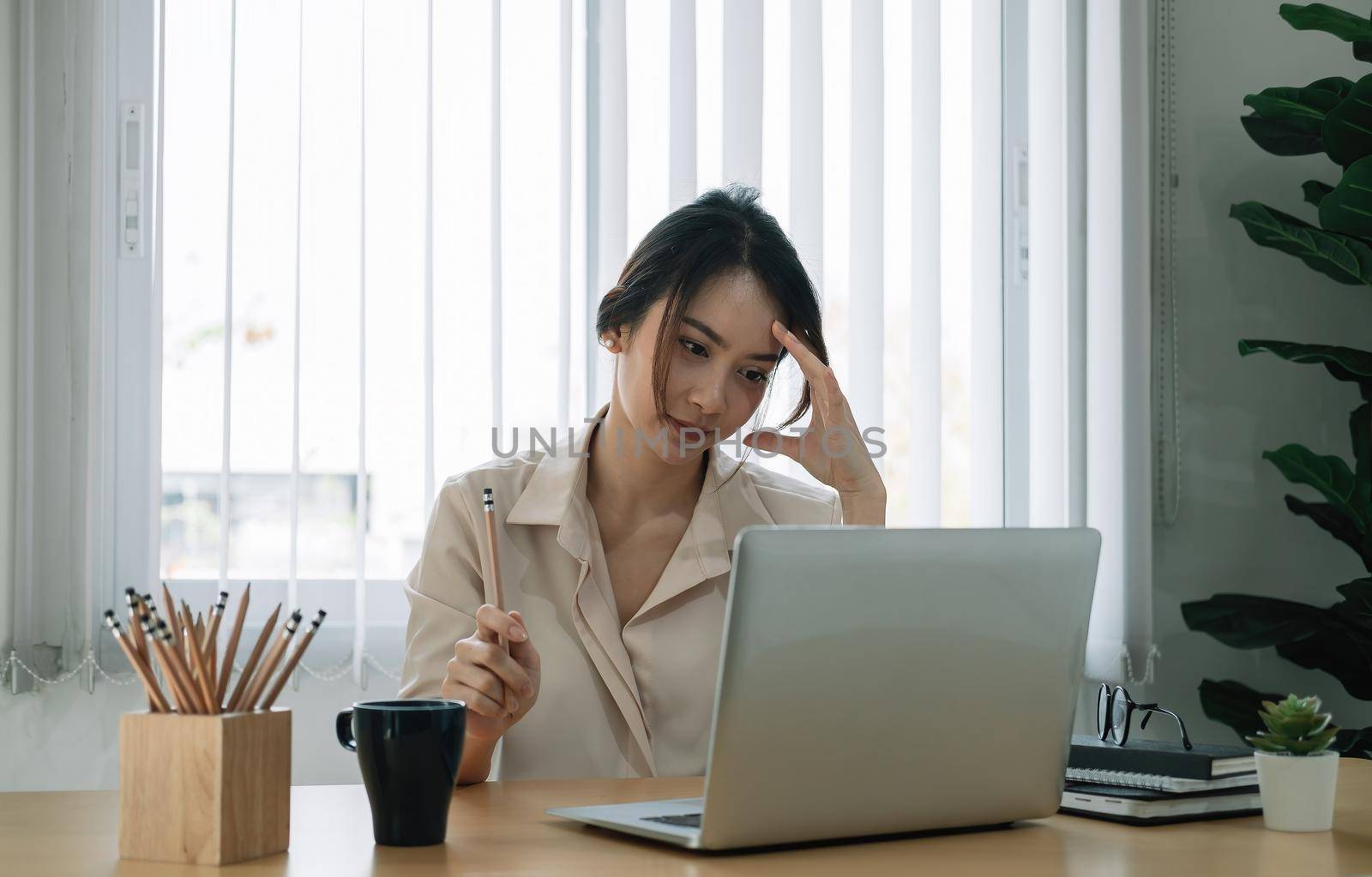 Portrait of business asian woman thinking and working with laptop computer in office,