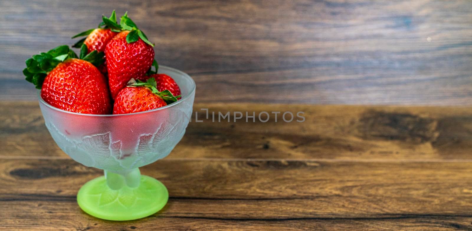 banner of a small cup of ripe strawberries on wood background