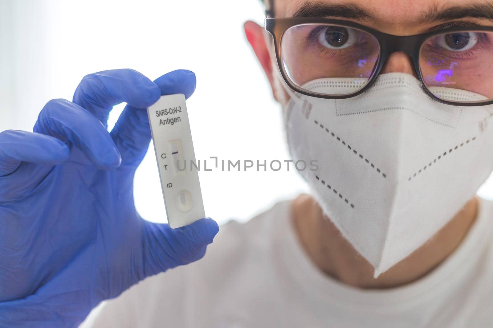 Young caucasian biologist or pharmacist is holding a covid-19 or corona antigen test by Daxenbichler