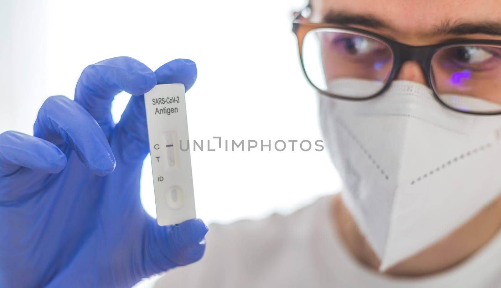 Young caucasian biologist or pharmacist is holding a covid-19 or corona antigen test by Daxenbichler