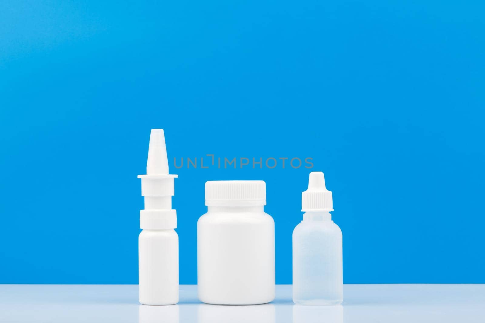 Nose spray, medication bottle and eye drops on white table against blue background with copy space. by Senorina_Irina