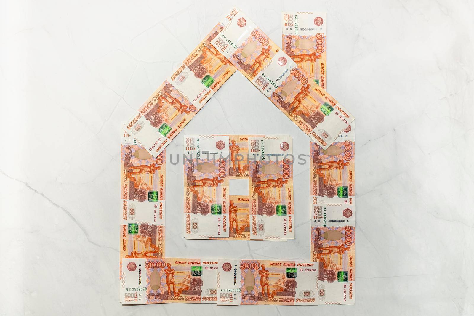 a house made of five-thousand-dollar bills on a marble background. High quality photo