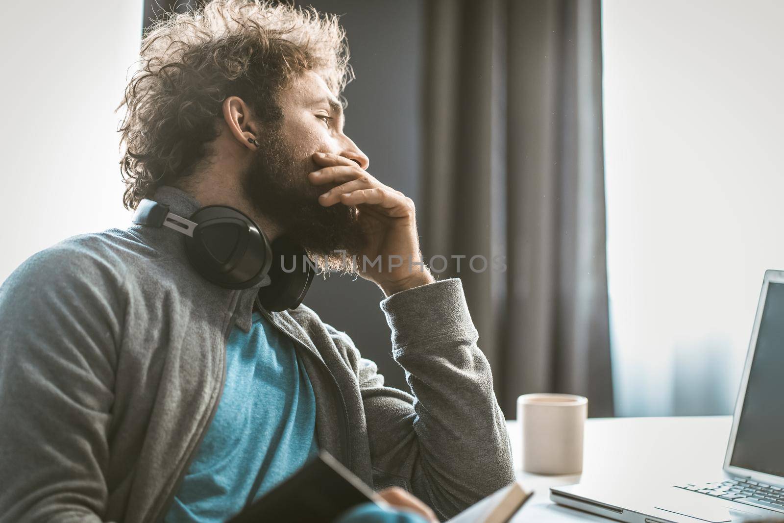 A young entrepreneur brings down accounting. The man takes notes in a notepad and looks at the computer screen sitting at his desk. High quality photo