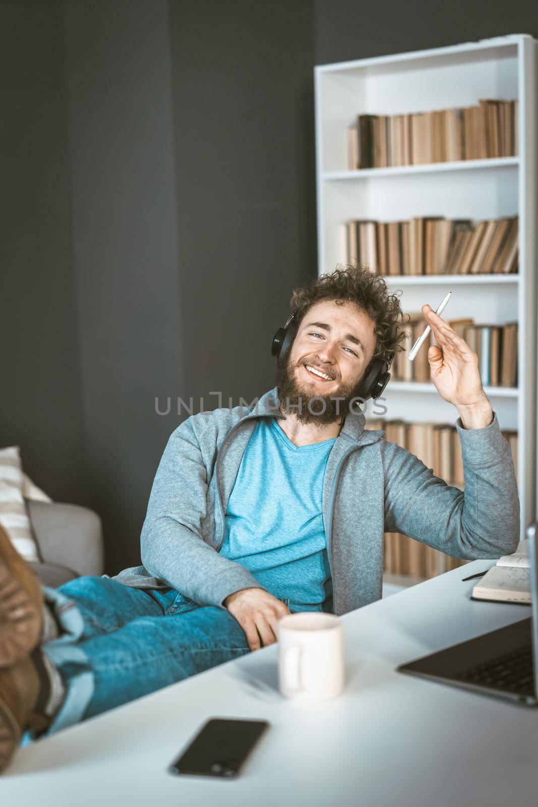 Happy student at home. Remote learning concept. Young man with headphones smiles sitting in front of a computer. High quality photo