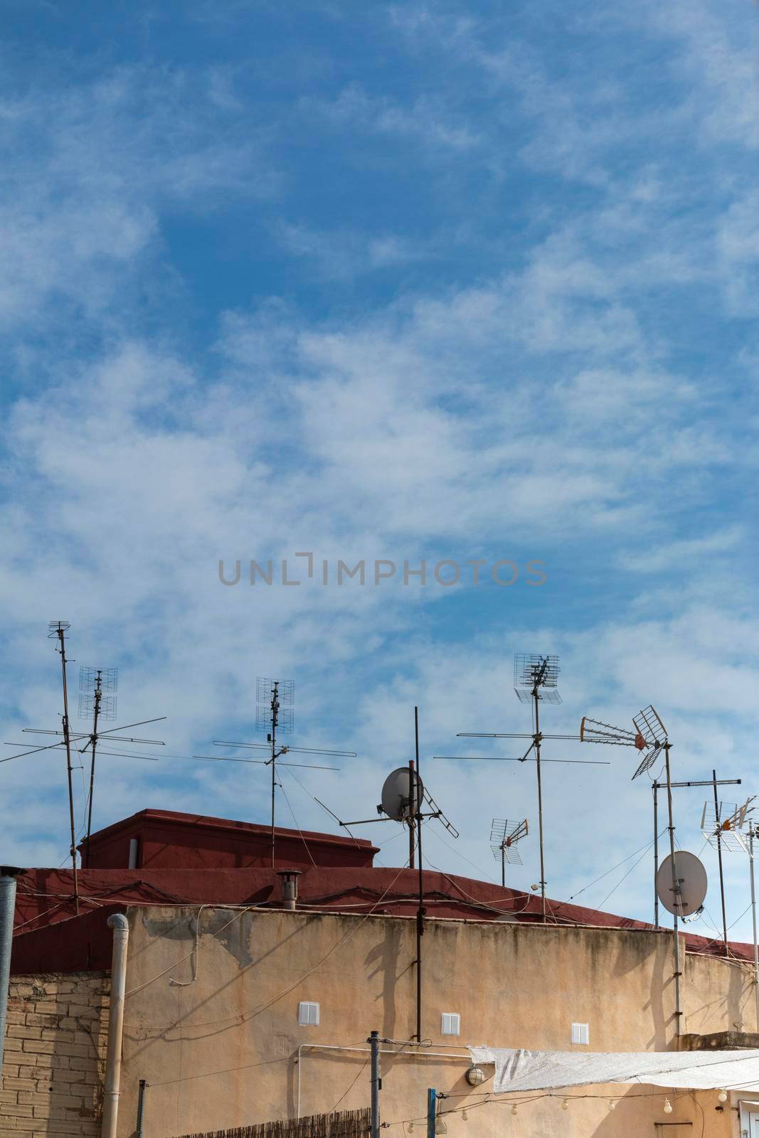 Rooftops with antennas in the countryside of a village in Spain by loopneo