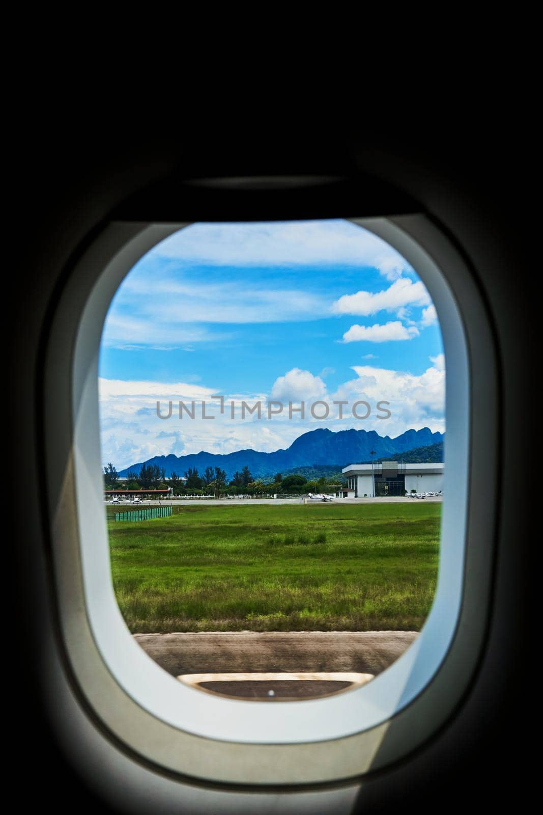 View from the window of an airplane on the runway of a tropical island.