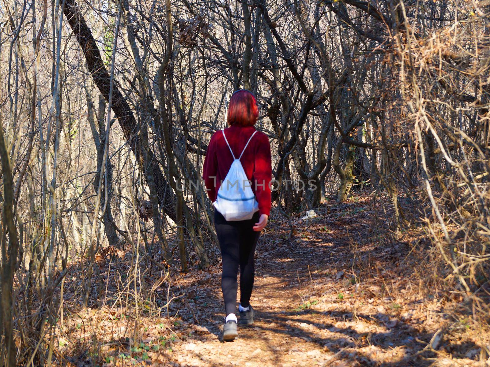 teenage girl in headphones goes along a forest trail with a backpack by Annado