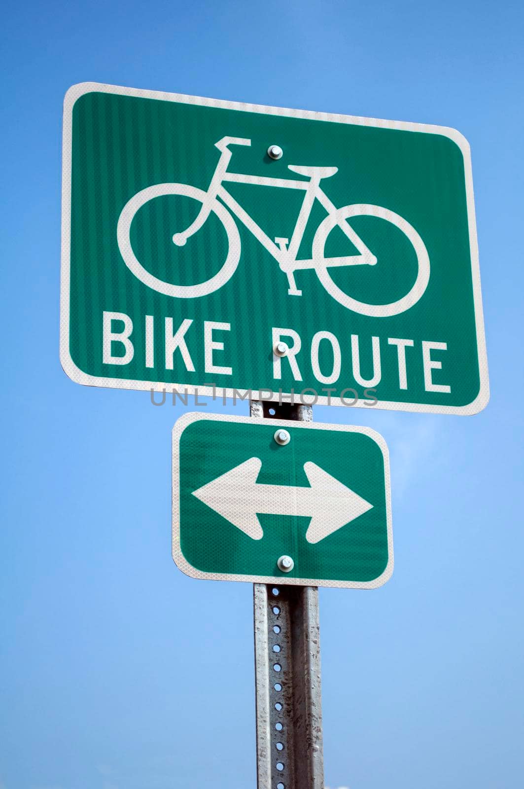 Green cyclist route traffic sign on blue sky.