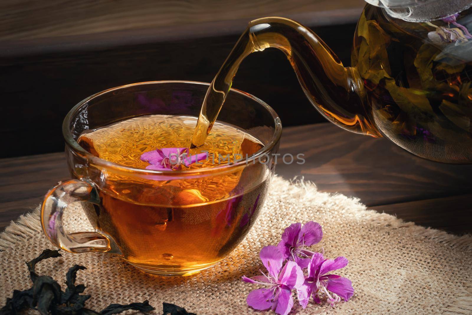 Pouring fireweed herbal tea into a transparent cup by galsand