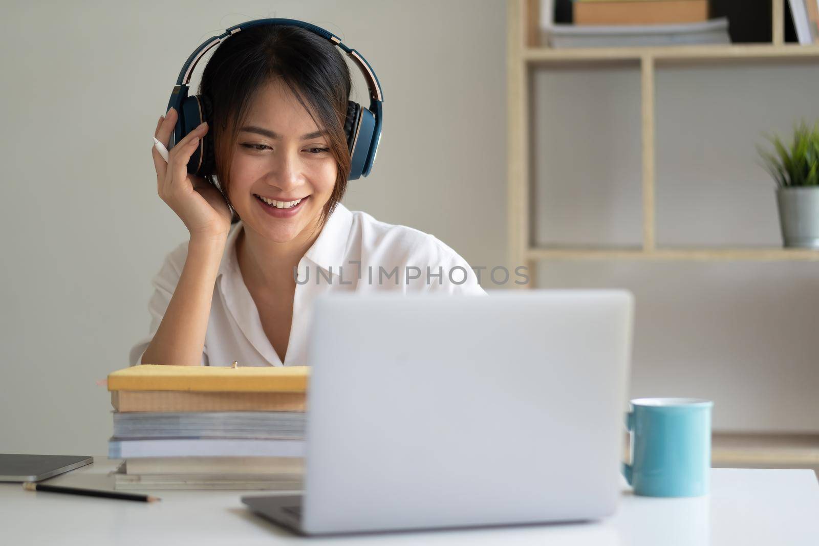 Asian woman wearing headphones study online watching webinar podcast on laptop listening learning education course conference calling, elearning concept