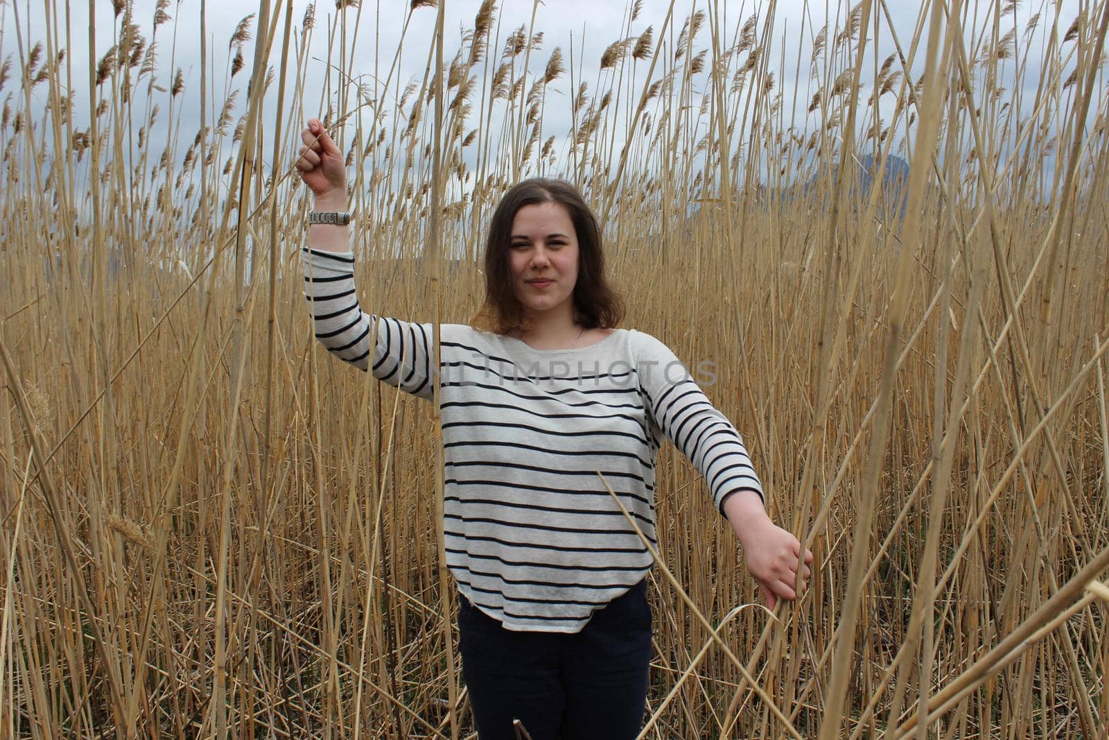 Portrait of a young girl in an outdoor field against a backdrop of wheat or tall grass. High quality photo