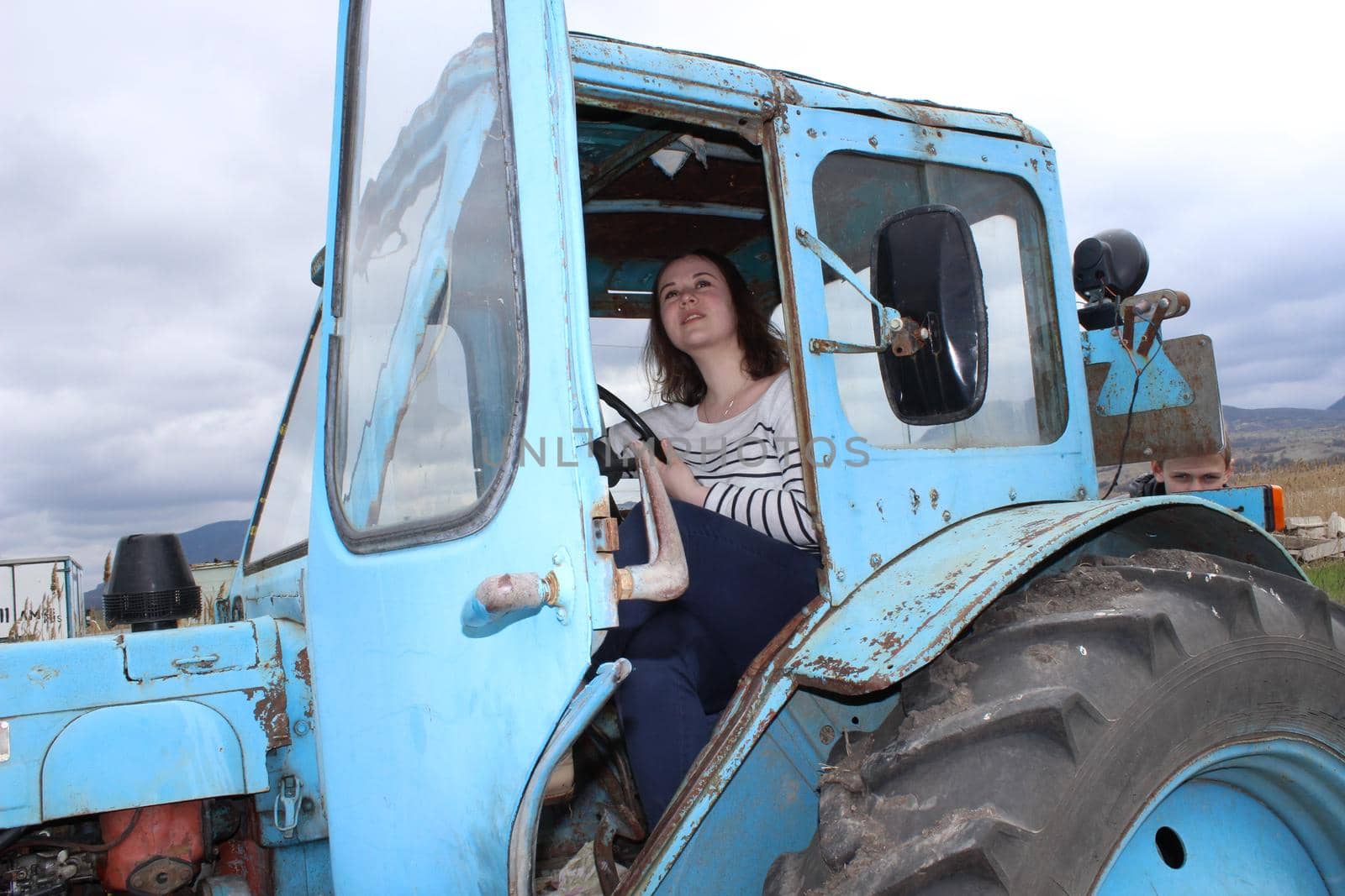 The girl on the tractor in the field. Plow the tractor land in the fall. Agricultural work. High quality photo