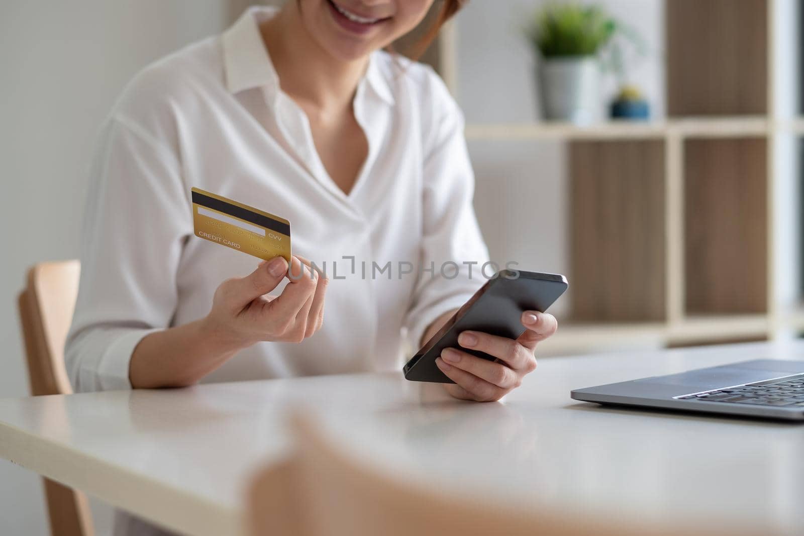 Woman paying with credit card on smart phone at home, online shopping concept
