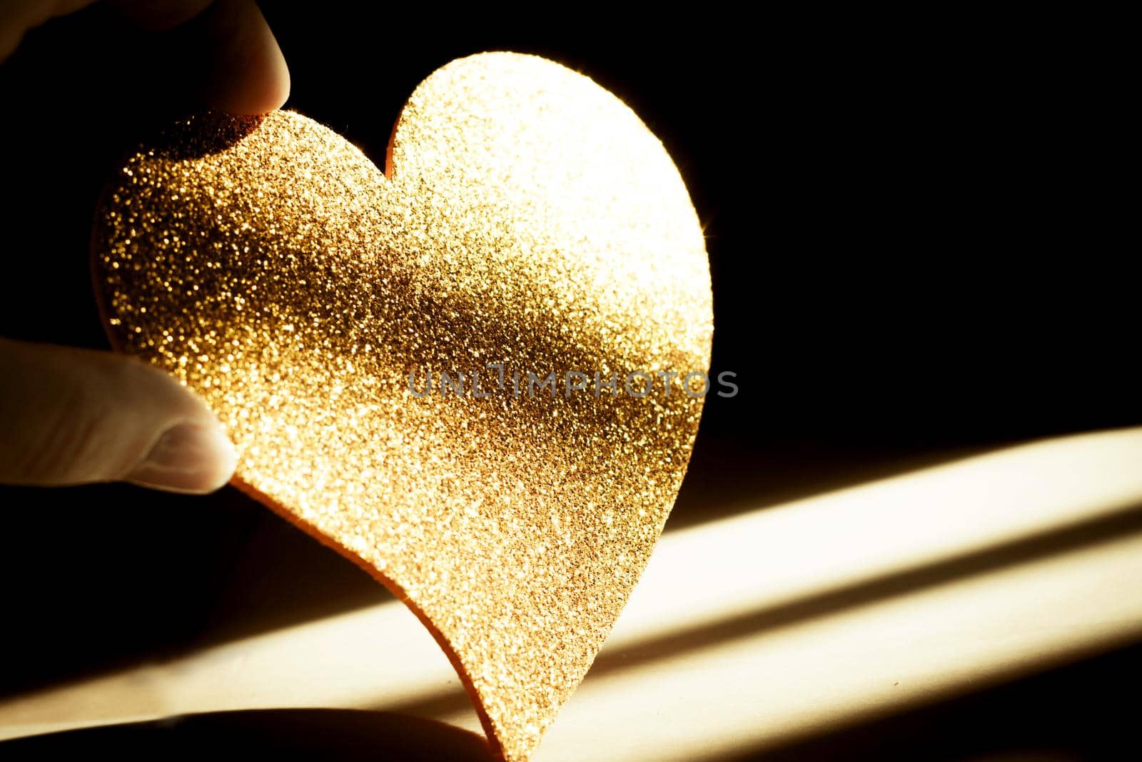 Golden shiny heart on black background
