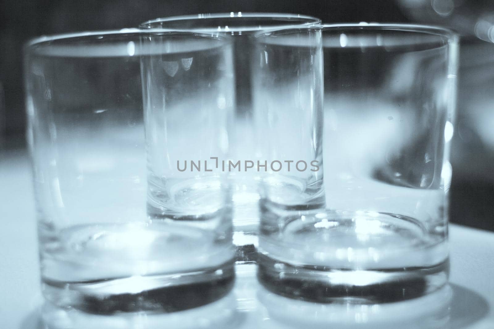 Three empty crystal glasses on dark background. No people