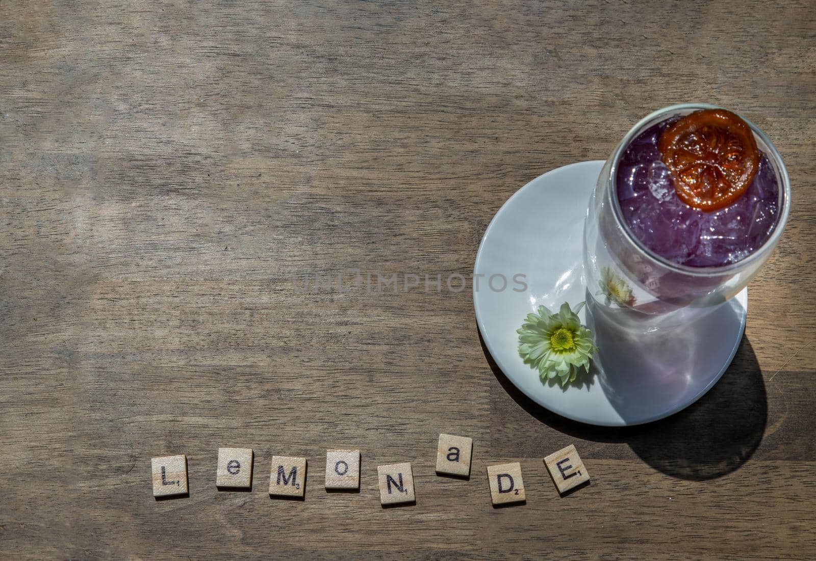 bangkok,Thailand - Feb 24, 2021 : Glass of soda drink with lemonade, orange mixer butterfly pea juice (Anchan) cold refreshing drink or beverage with ice on wooden table. Copy space, Selective focus.