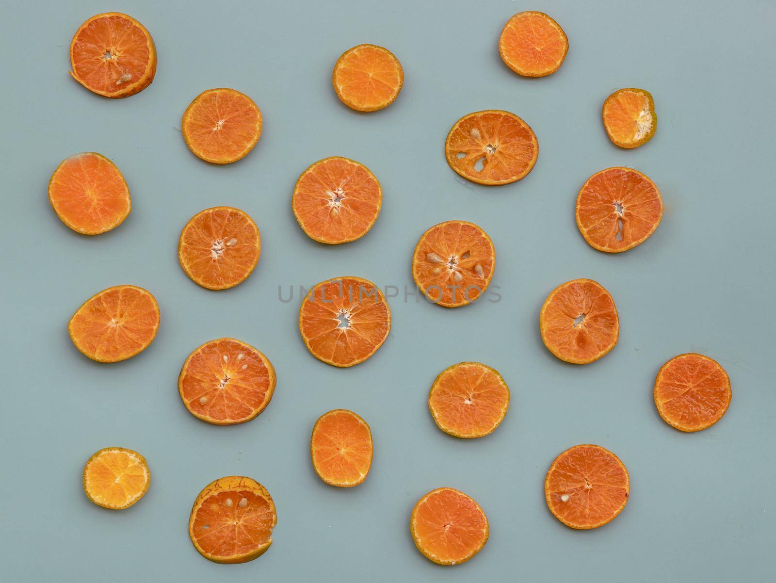Top angle view of slice oranges in a pattern on green background. Selective focus.