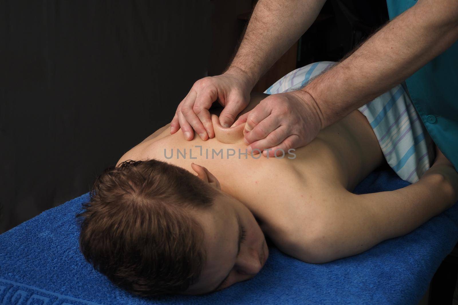 The back massage is manual. The specialist massages the back of the patient lying on the massage couch. High quality photo