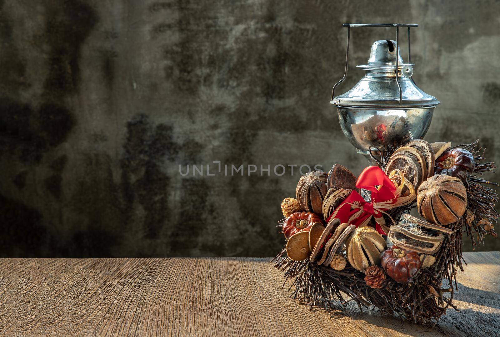 Different Dry fruits on a twigs pile shape of heart with ancient kerosene (oil) lamp on wooden background with old cement wall. Copy space, Selective focus.