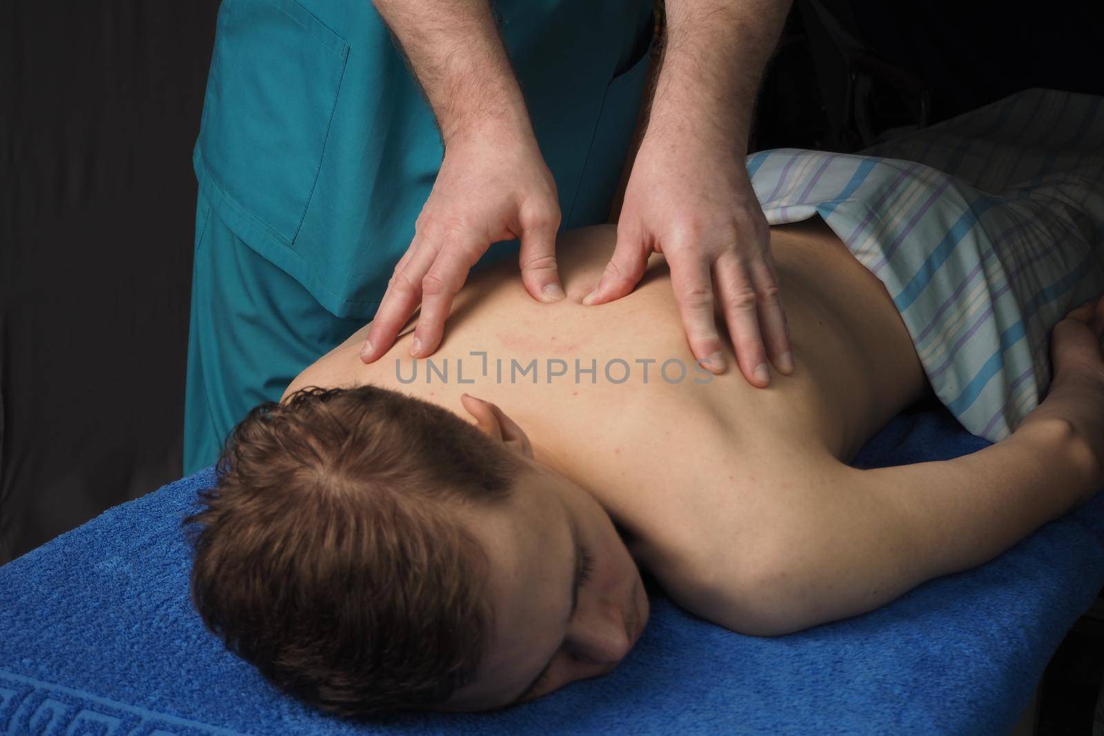 The back massage is manual. The specialist massages the back of the patient lying on the massage couch. High quality photo