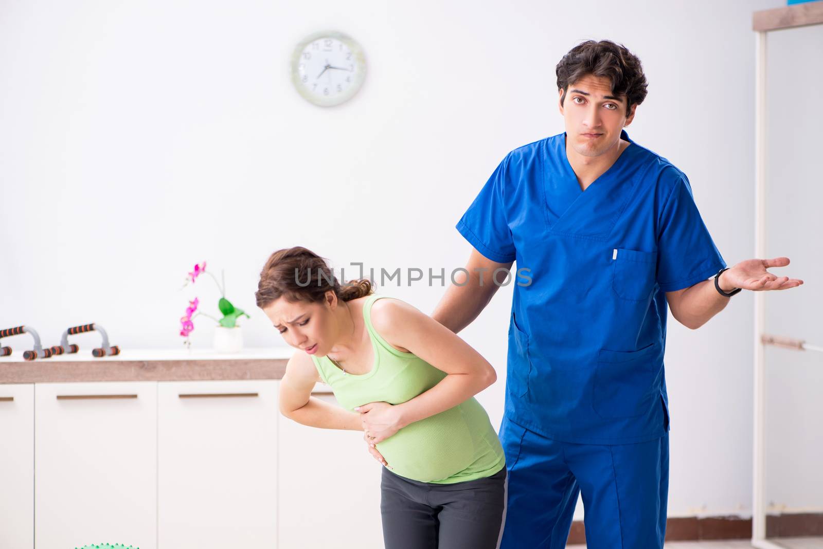 Pregnant woman doing physical exercies with instructor