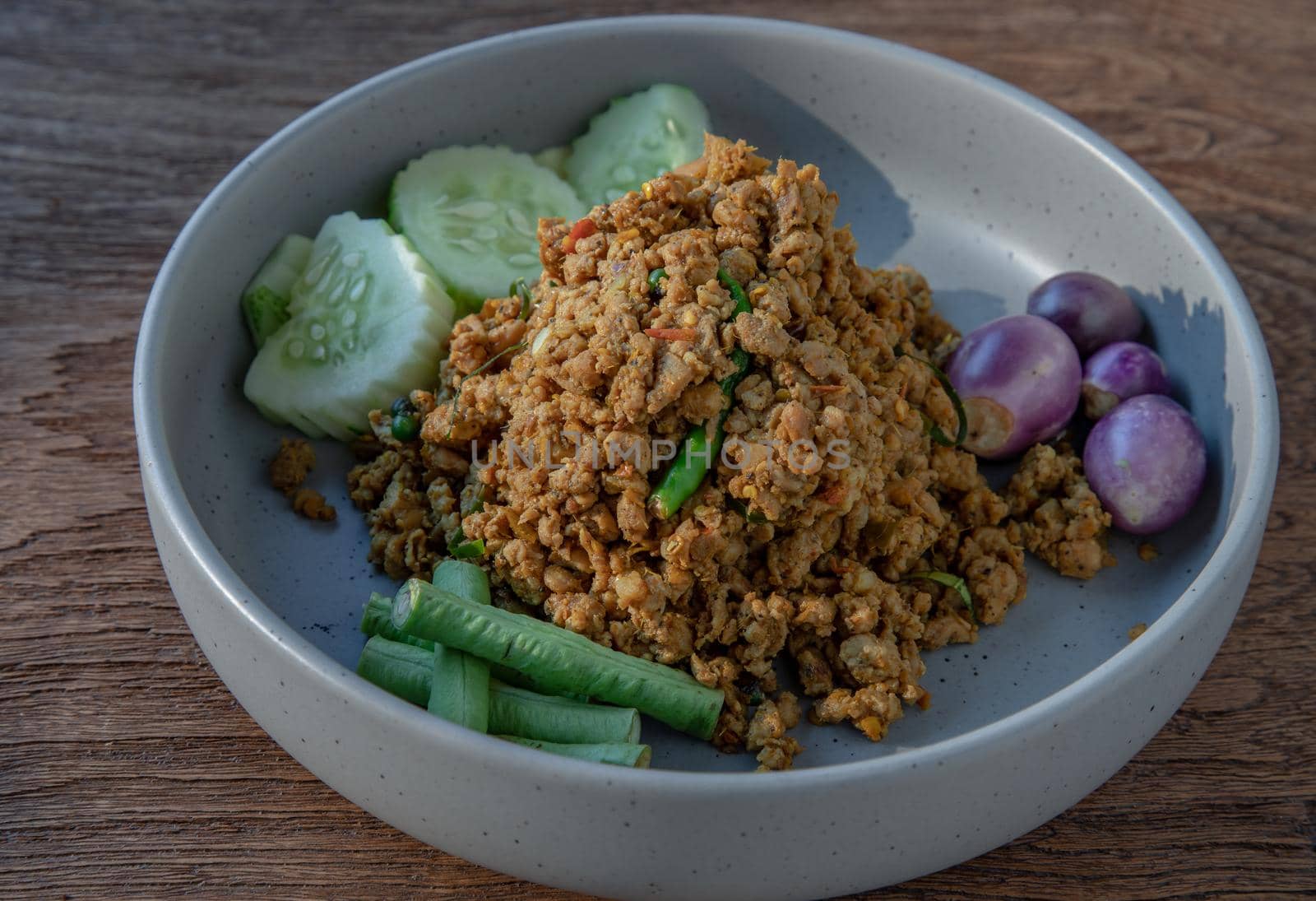 Southern Stir-Fried Pork with Yellow Curry Paste Served with Purple eggplant, Cucumber and Yard long bean. Selective focus.