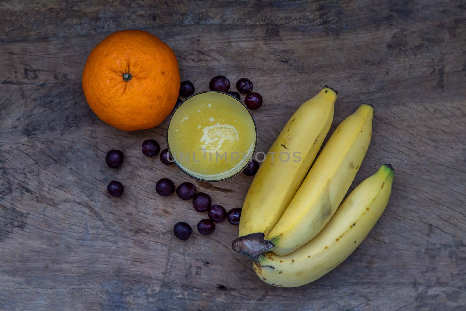 Healthy ripe Yellow Mango Smoothie in Glass and Banana, Orange and Grape rustic old wooden table. Tropical fruit concept. Selective focus.