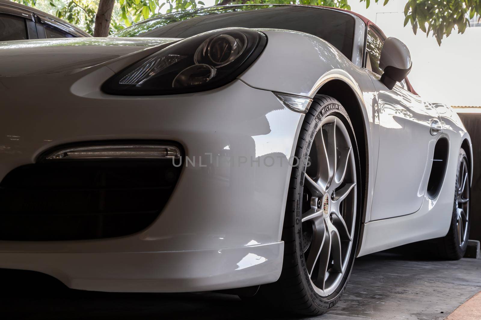 Bangkok, Thailand - 14 Jan 2021 : Close-up of Car Headlights and Car Wheel of White Porsche Sports Car parked in the parking lot. Selective focus.