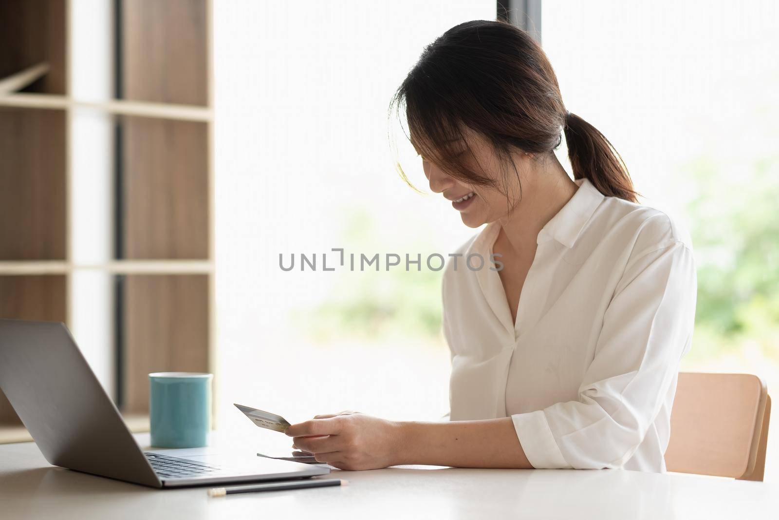 Shot of woman hands holding credit card and smartphone paying online, using banking service, entering information, shopping, ordering in internet store, doing secure payment