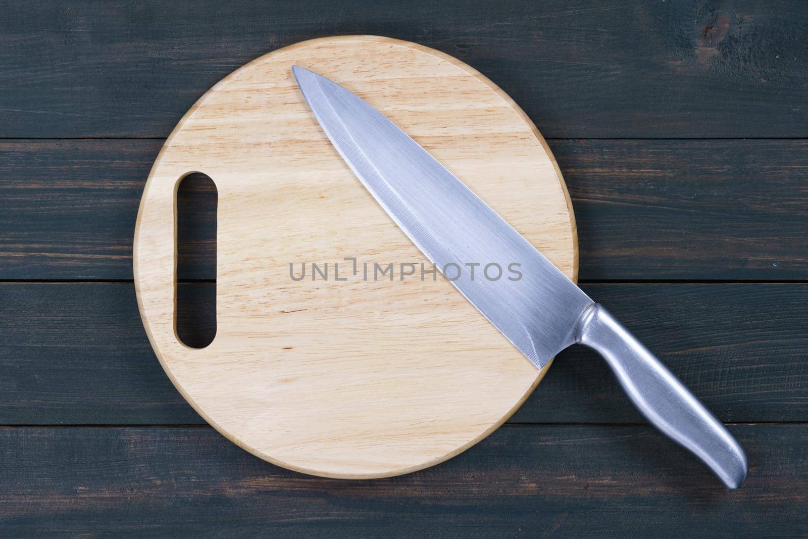 Close up kitchen knife and wooden round empty cutting board on a wooden table