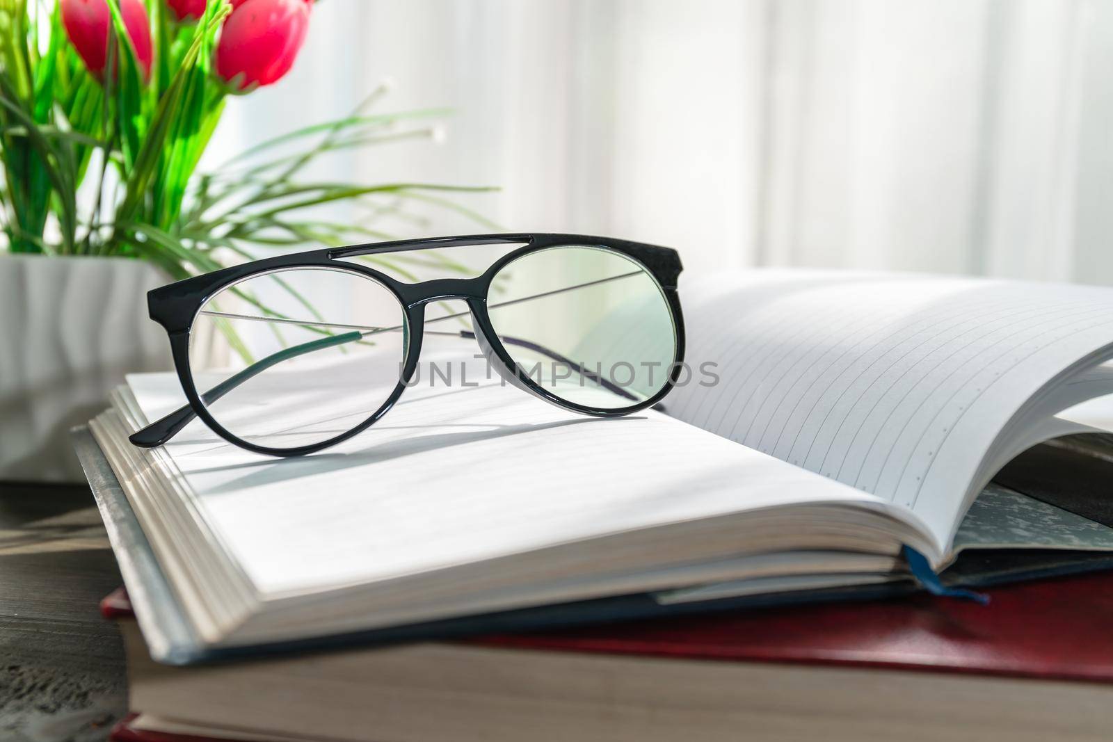 Reading glasses put on open book beside the window by stoonn