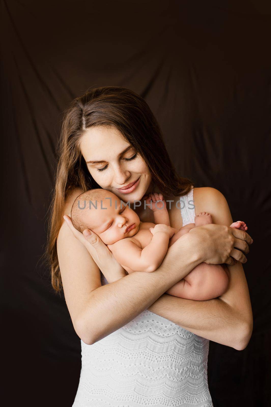 Mother holding her newborn daughter in her arms at a newborn photoshoot. High quality photo