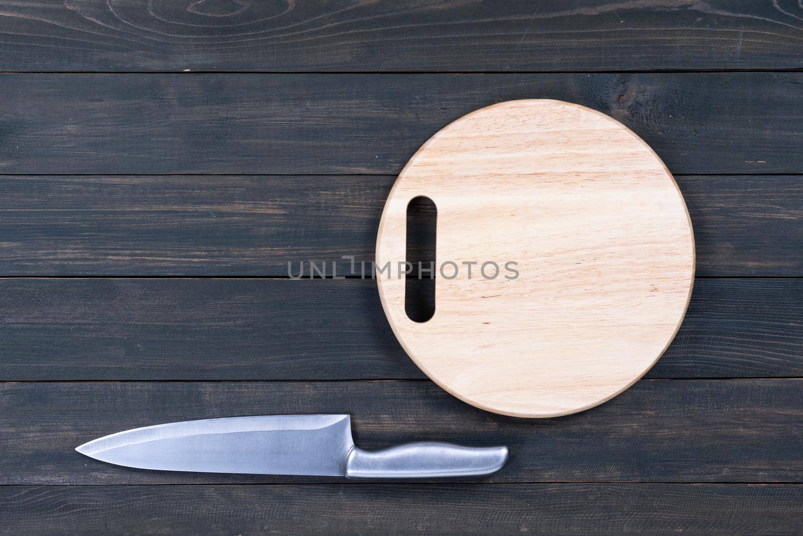 kitchen knife and wooden round empty cutting board on a wooden table close up