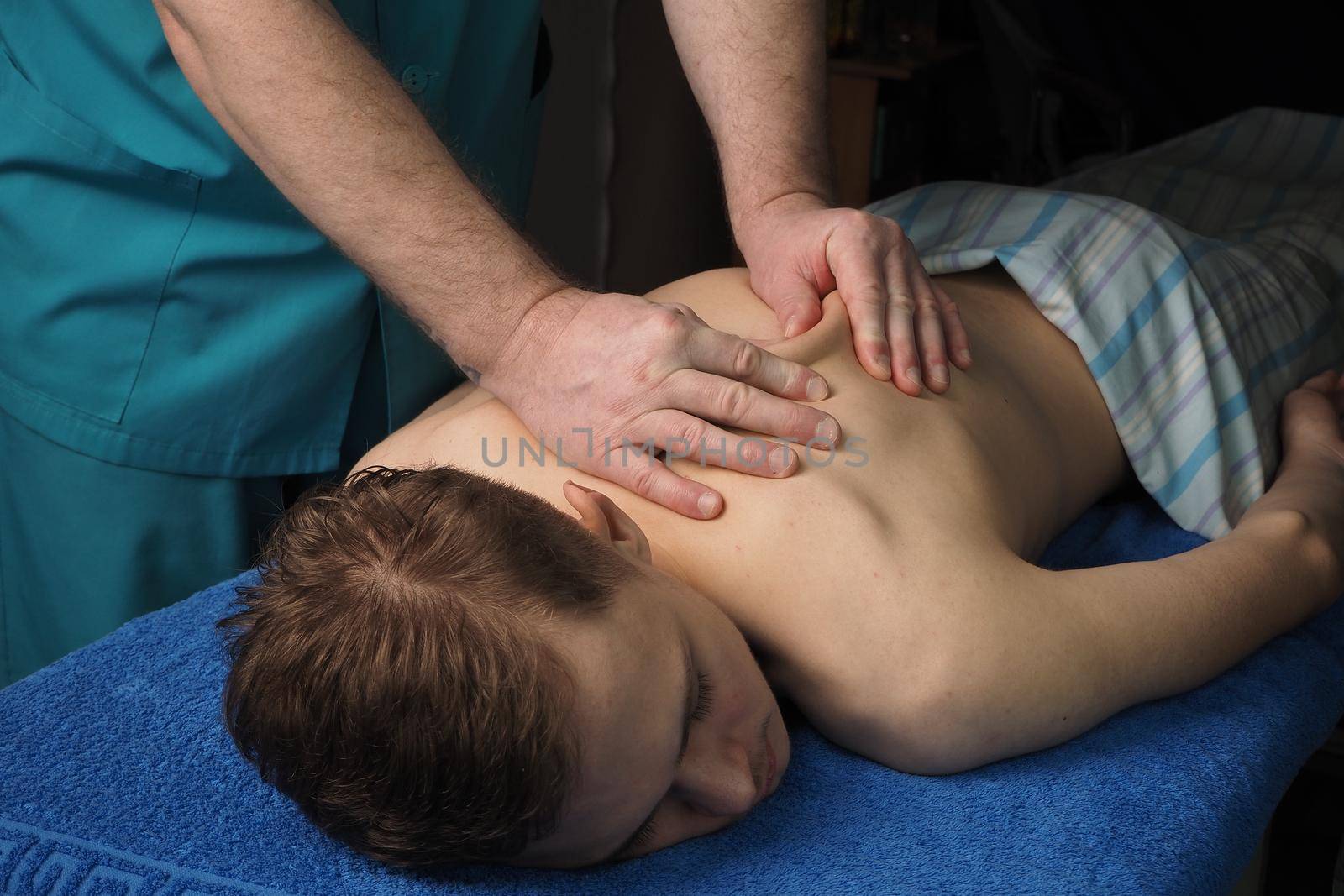 The back massage is manual. The specialist massages the back of the patient lying on the massage couch. High quality photo. High quality photo