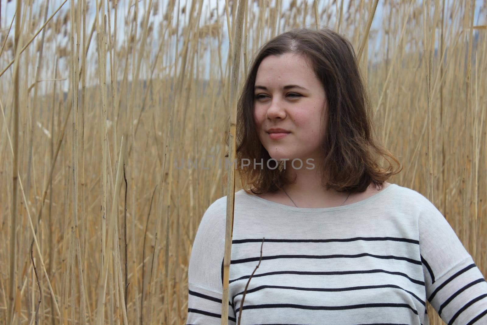 A young girl in an outdoor field against a backdrop of wheat or tall grass. by Olga26