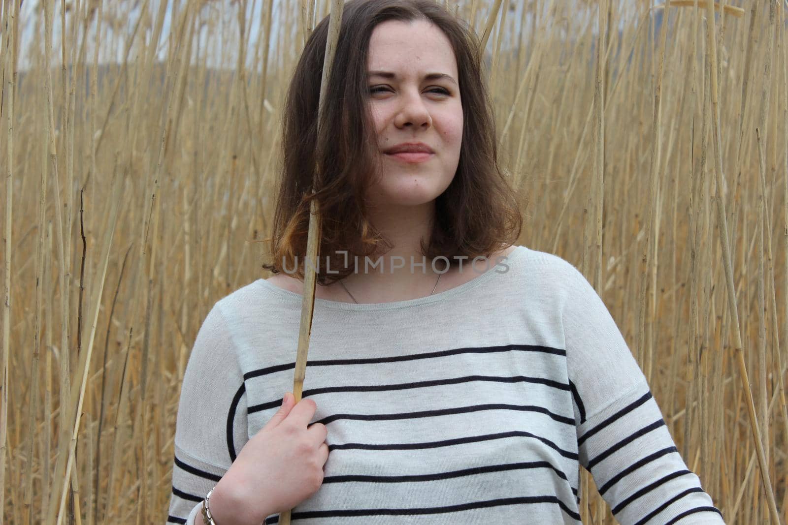 Portrait of a young girl in an outdoor field against a backdrop of wheat or tall grass. High quality photo