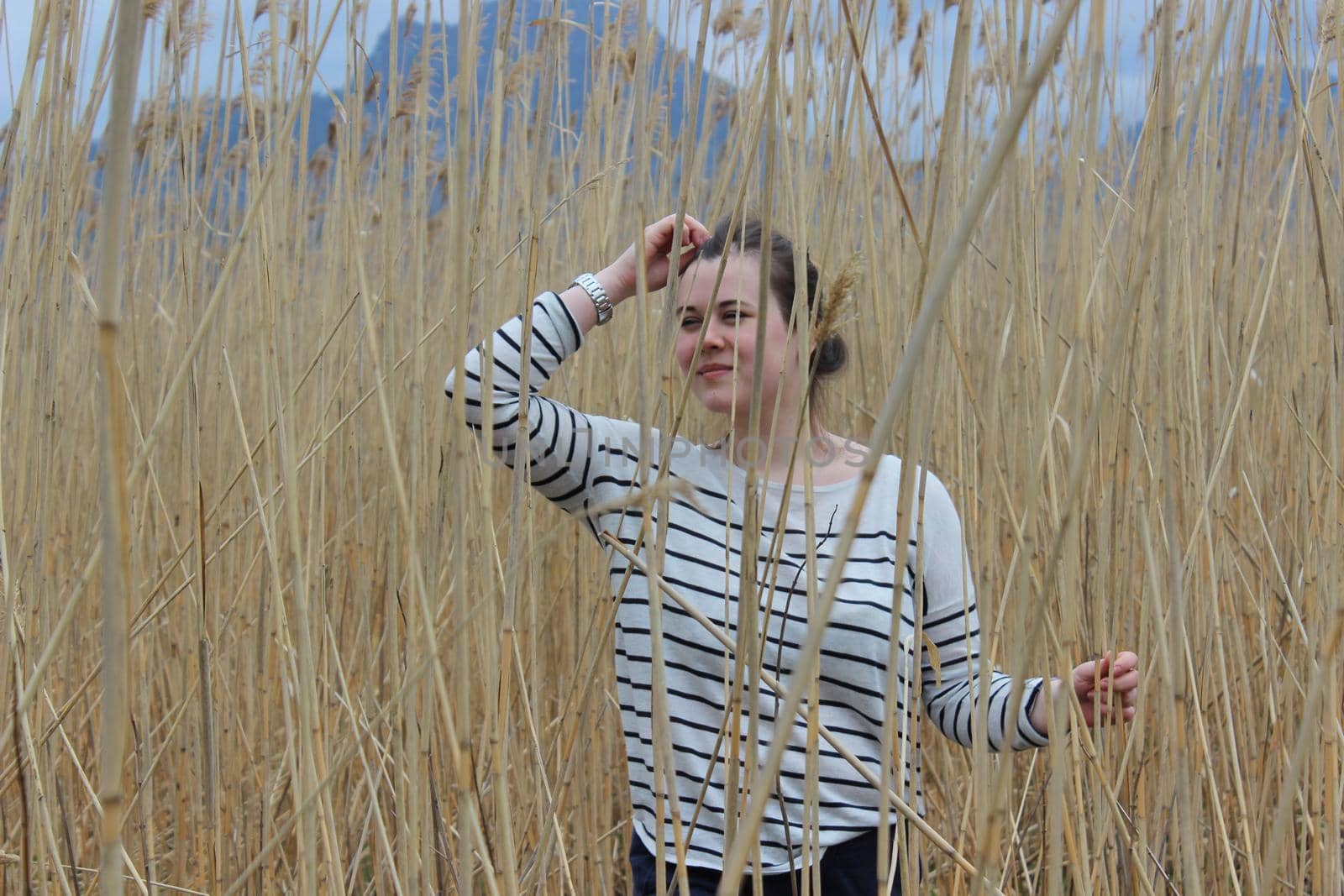 A young girl in an outdoor field against a backdrop of wheat or tall grass. by Olga26