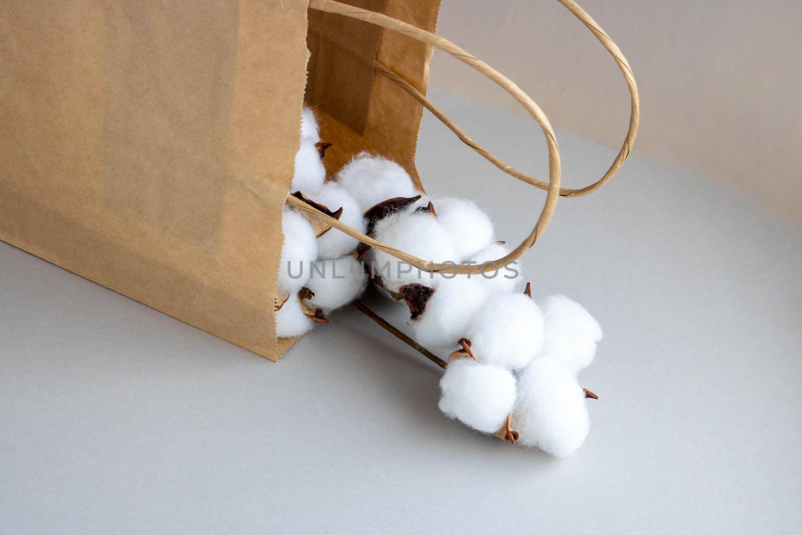 Organic eco-friendly paper bag with cotton flowers on a gray background. Zero waste and eco-friendly concept.